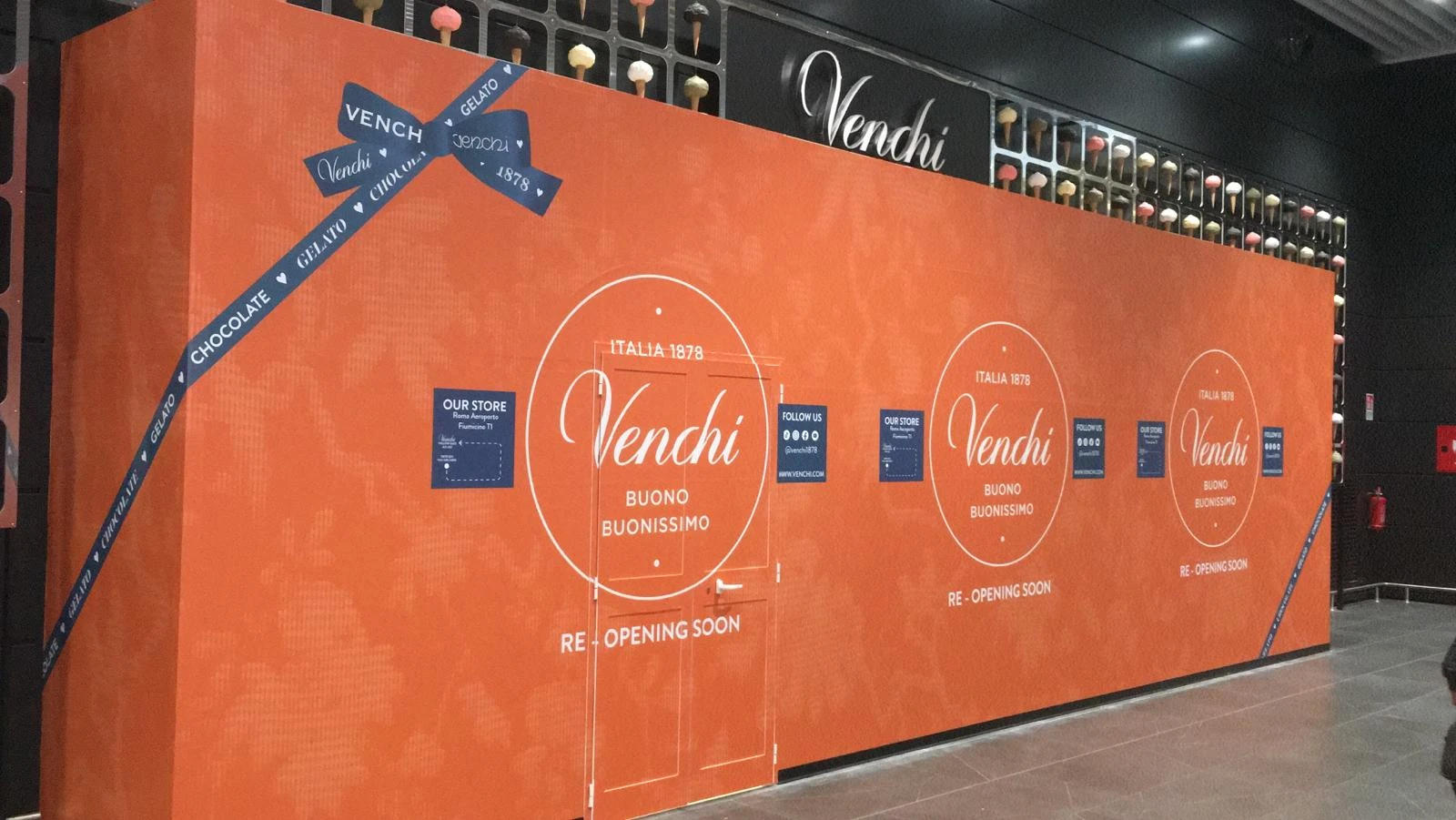 Per Venchi, storico marchio italiano del cioccolato e del gelato, abbiamo realizzato la copertura e decorazione temporanea del punto vendita durante il periodo di restyling. Il design, ispirato all’immagine elegante e colorata del brand, trasforma il cantiere in un grande packaging esperienziale, immediatamente riconoscibile e perfettamente in linea con lo stile Venchi. Un progetto che unisce cura estetica, materiali di qualità e attenzione ai dettagli, per comunicare il gusto e la raffinatezza del marchio anche a porte chiuse.